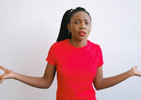 Young black woman in a red shirt with a confused expression. Perfect for emotive stock photo needs.