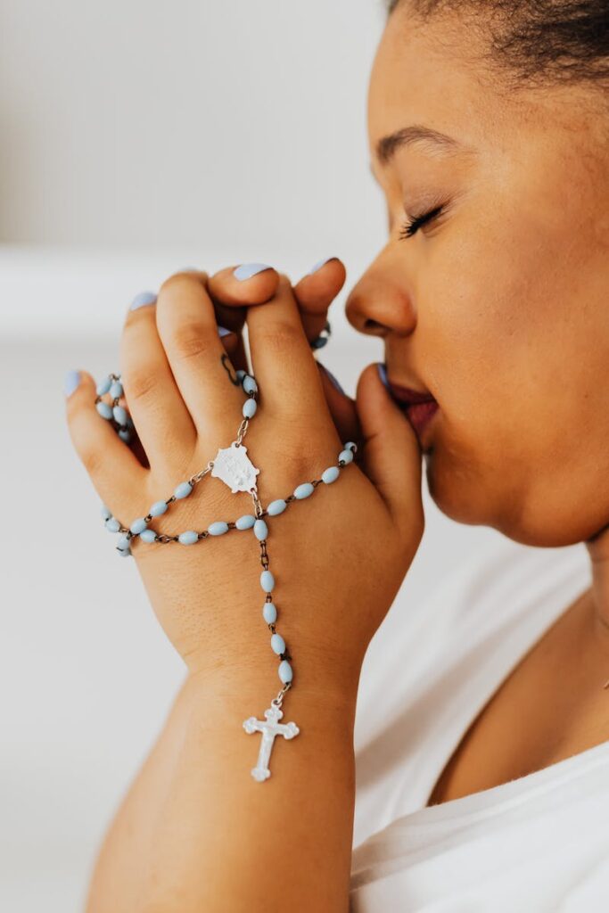 Faith Talk Close-up of a woman with eyes closed, holding rosary beads in prayer.